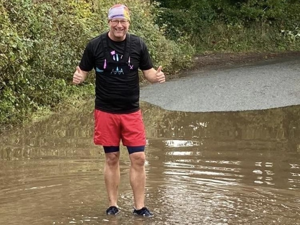 A man in a Lily top standing in ankle-deep water on a flooded lane